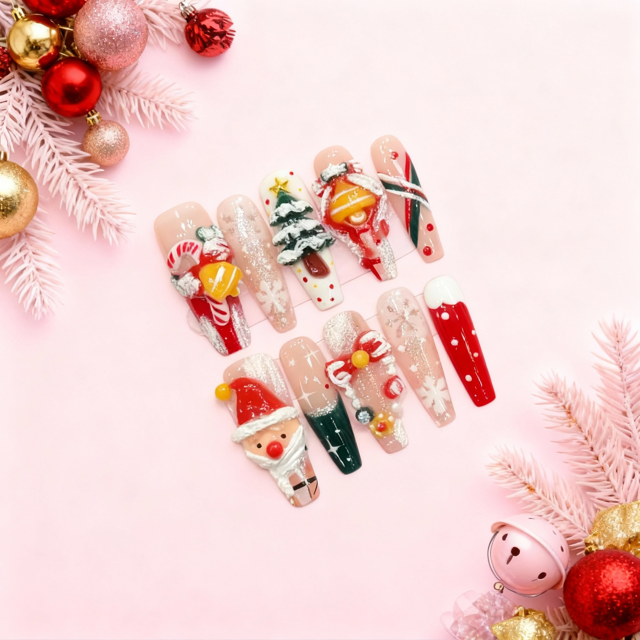 3D Christmas press-on nails with Santa, candy cane, stocking, snowflakes and holiday charms in red, green, gold and nude on pink festive background.
