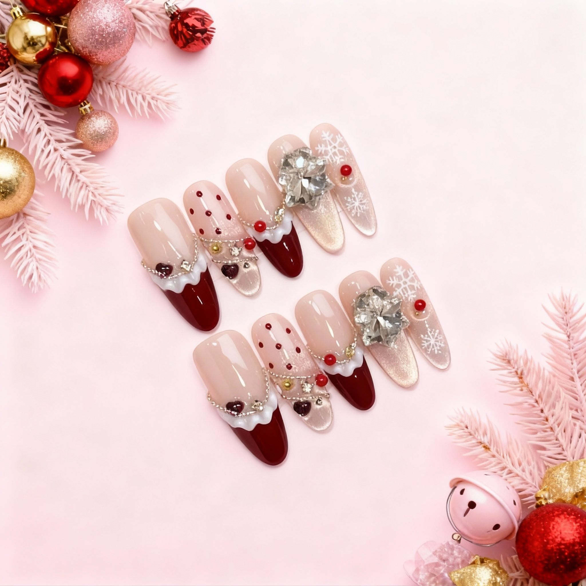 Christmas Soirée Glow press-on nails with nude and burgundy French tips, crystal bows, red dot accents, and white snowflake designs on a soft pink holiday background