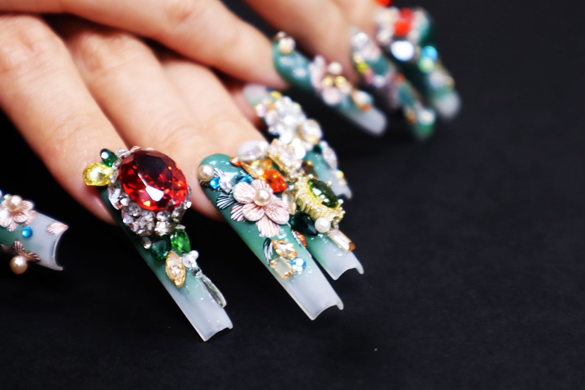 Close-up of luxury press on nails featuring oriental embroidery textures and sculptural gemstone nail art