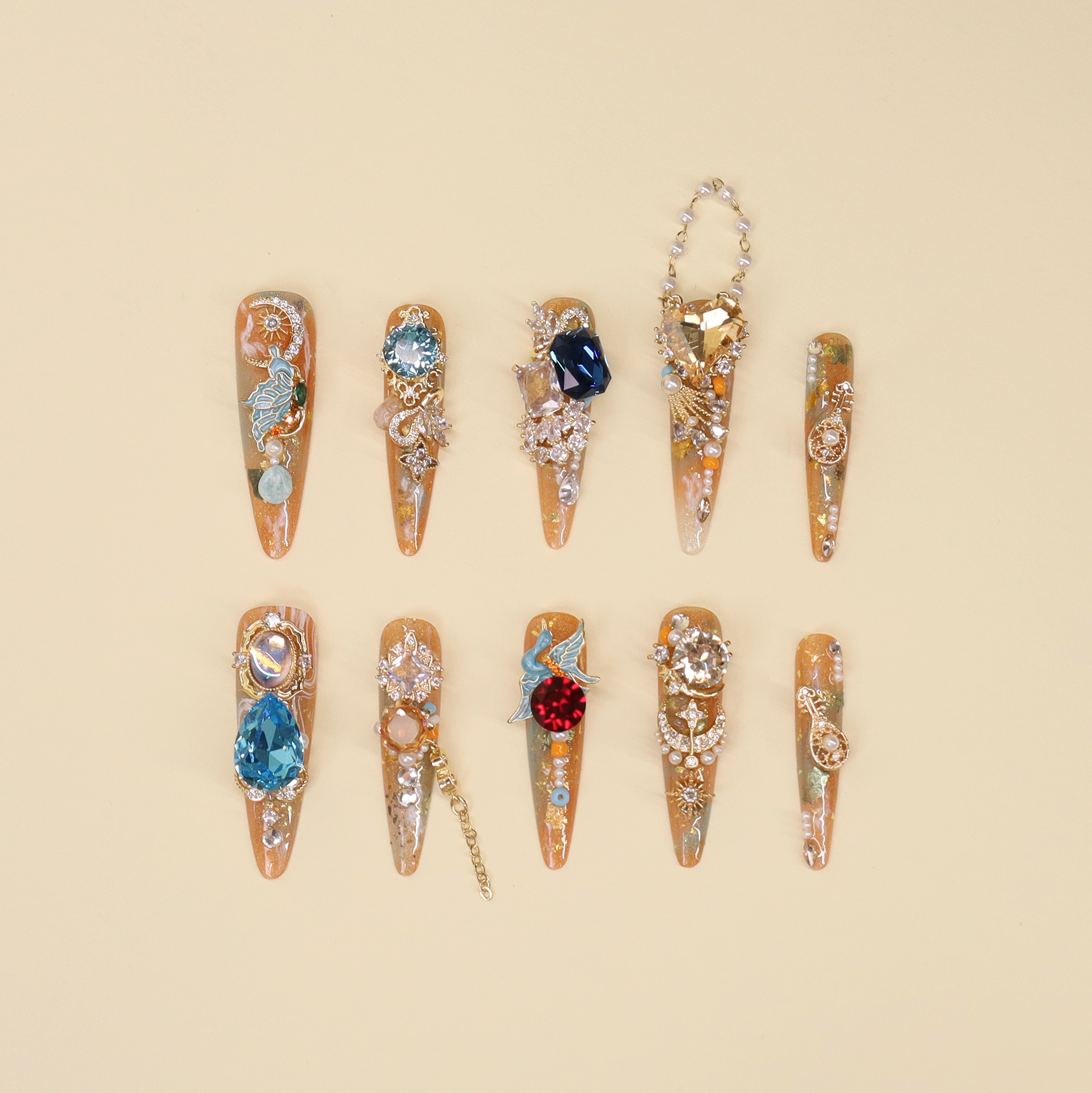 Luxury press on nails “Silk Road” featuring amber, gold, blue gemstone designs with pearls and sculptural crystal details on a soft background