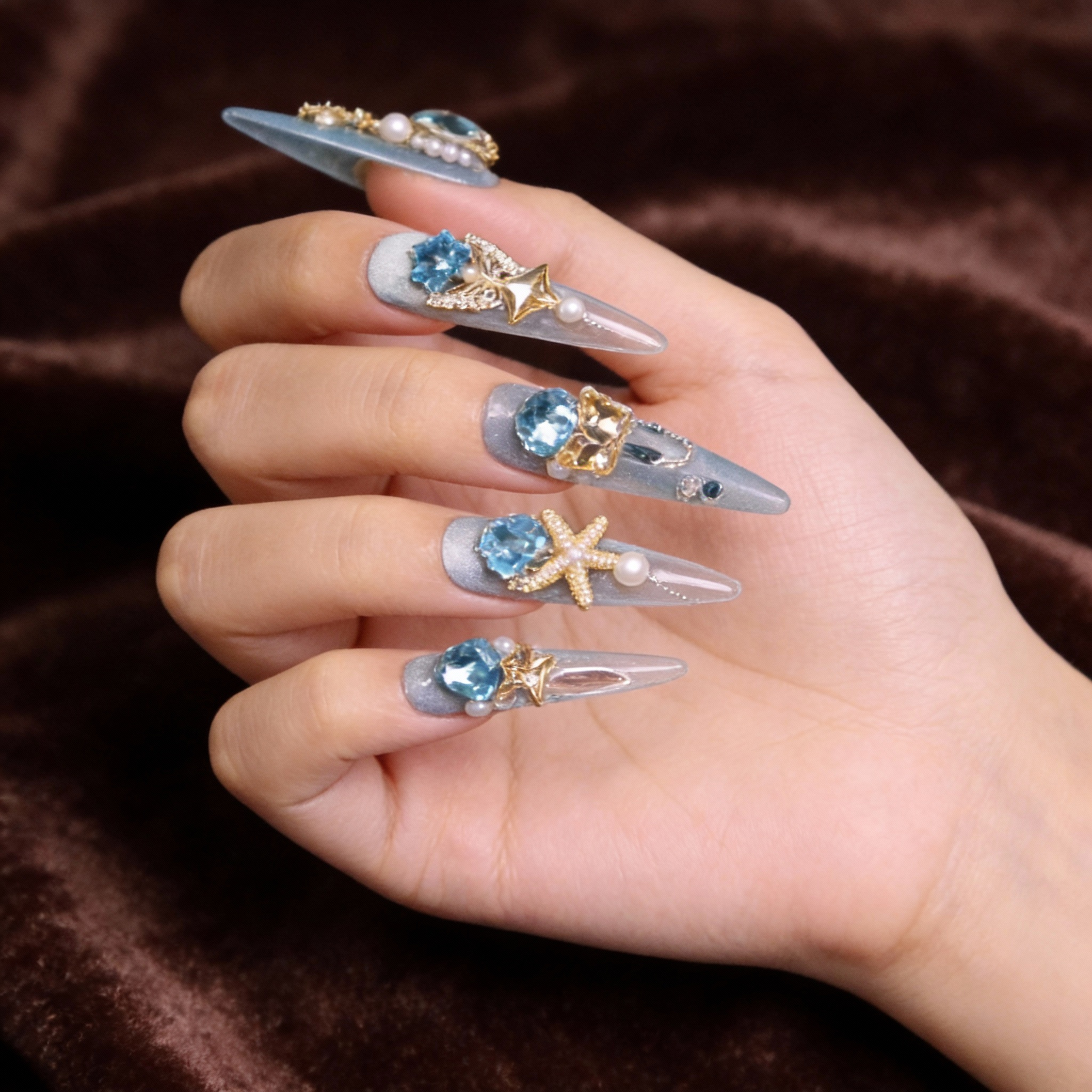 Mera Queen of Atlantis luxury press on nails worn on hand, ocean blue nails with crystal, pearl, and mermaid tail embellishments