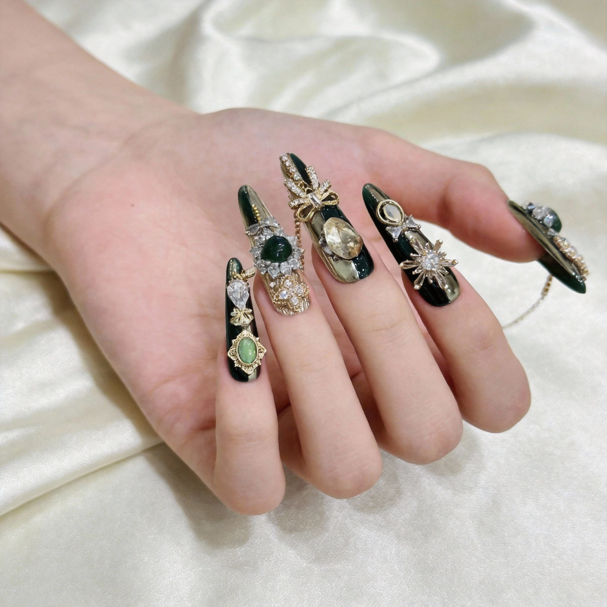 Close-up of green press-on nails with gold-toned decorative details