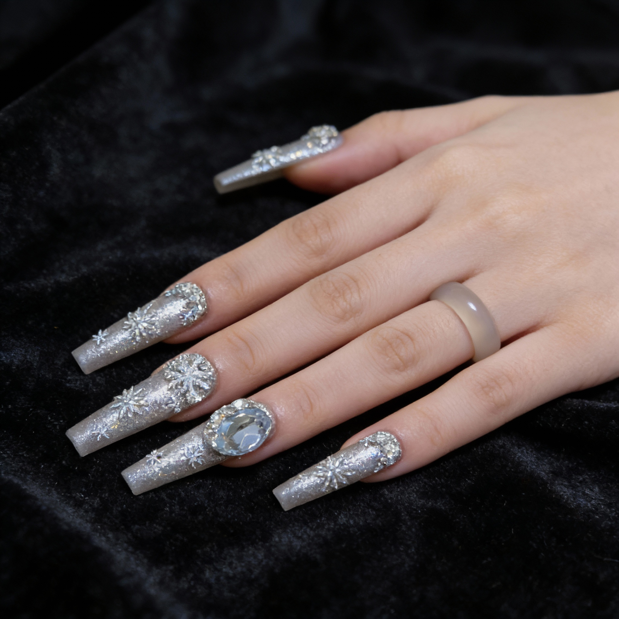 Hand model wearing Snowfall Day winter nails with cool silver glow and clean glass-like texture