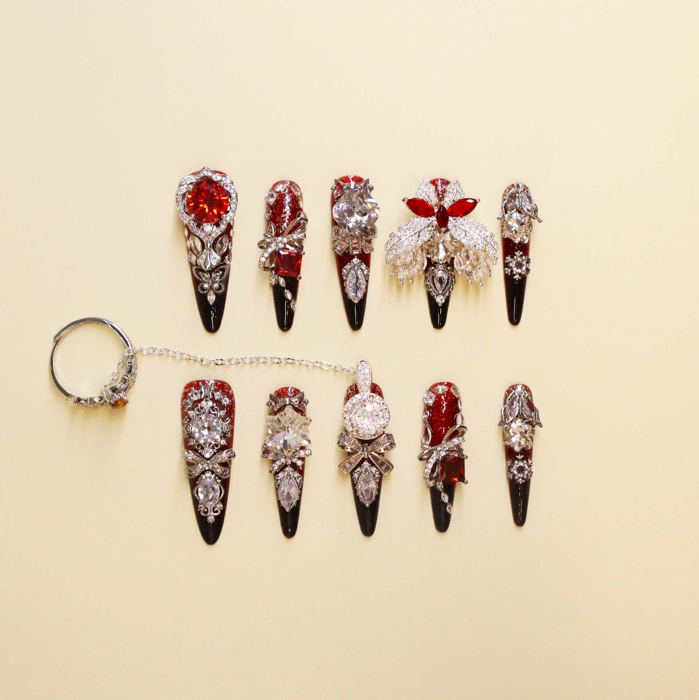 Crimson Seraph luxury press-on nails with red and black gradient, blood-red crystal, silver wing detail, and statement nail ring
