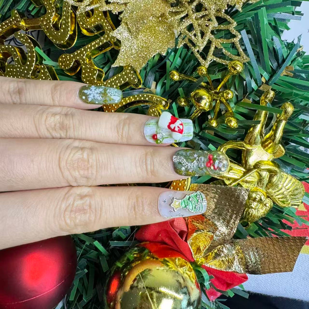 Festive green Christmas nails with 3D charms, snowflake art and cat-eye shimmer, photographed with snowy holiday decorations.