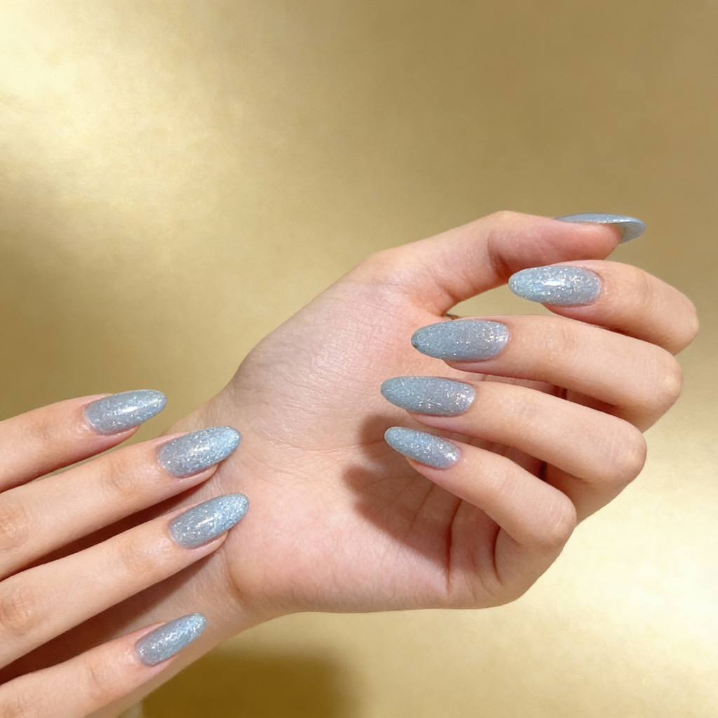 Icy Blue Sparkle winter sparkly nails worn on hand, showcasing a soft icy blue shimmer under natural light.