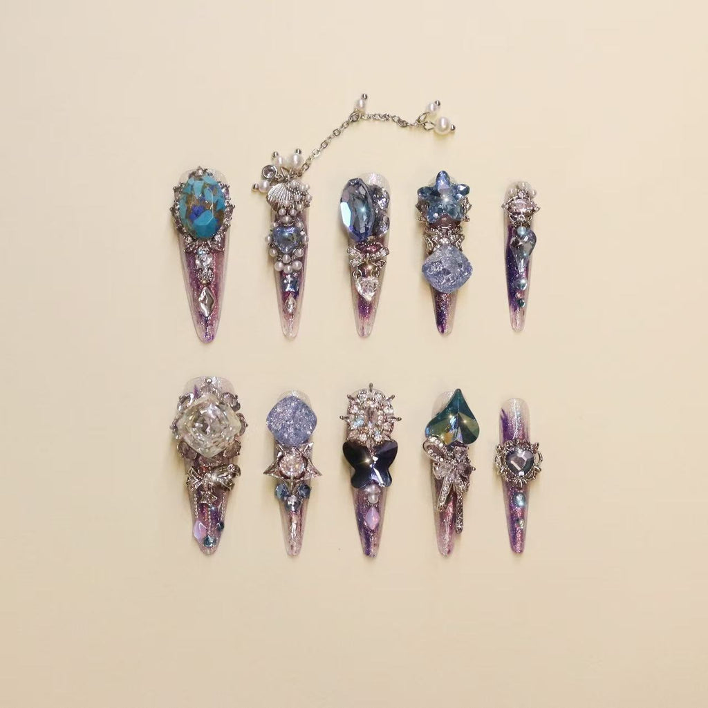 Luxury purple press-on nails with butterfly charms and gemstone crystal details, featuring gradient violet shimmer and high-end 3D nail art design.