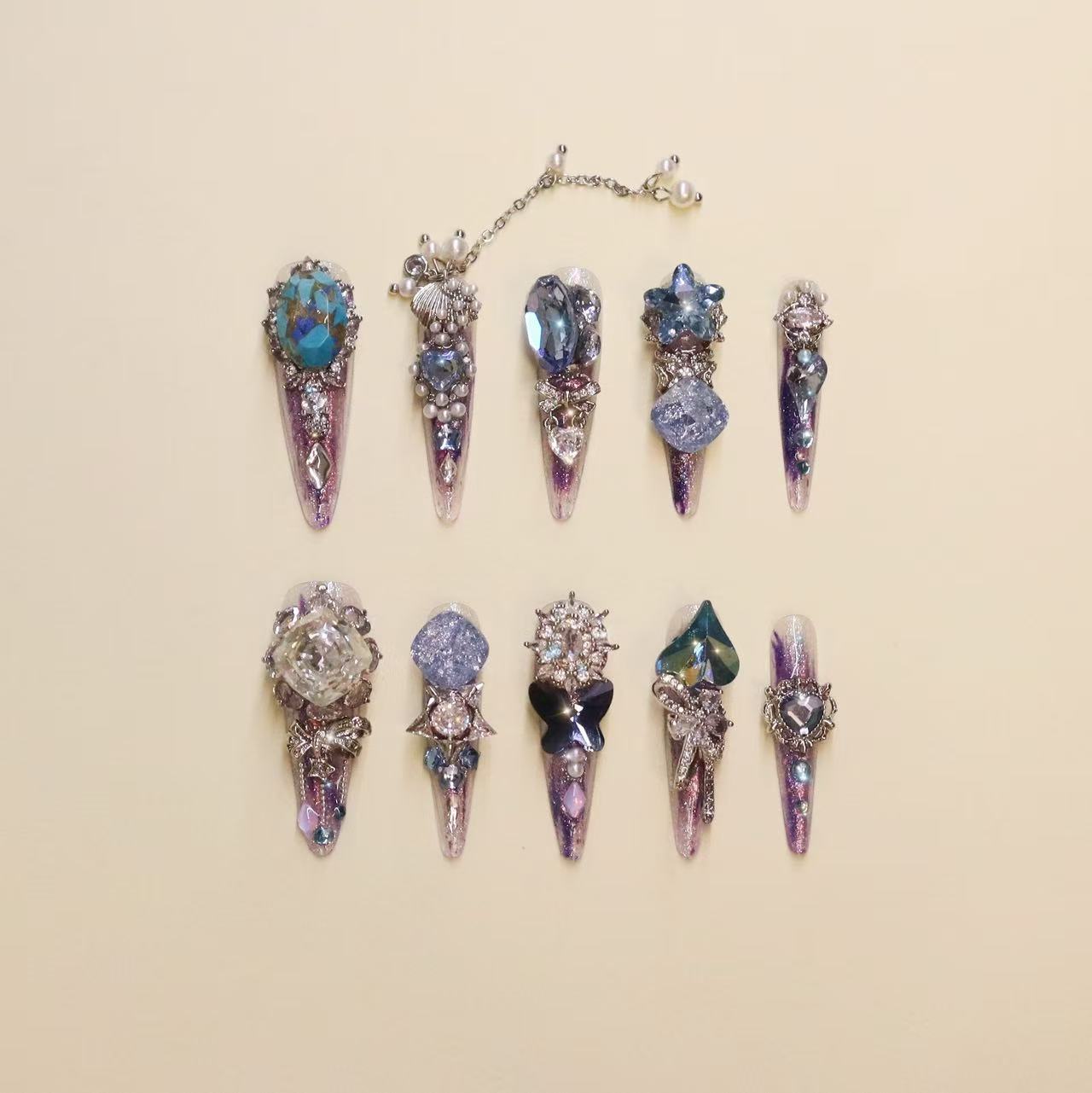 Luxury purple press-on nails with butterfly charms and gemstone crystal details, featuring gradient violet shimmer and high-end 3D nail art design.