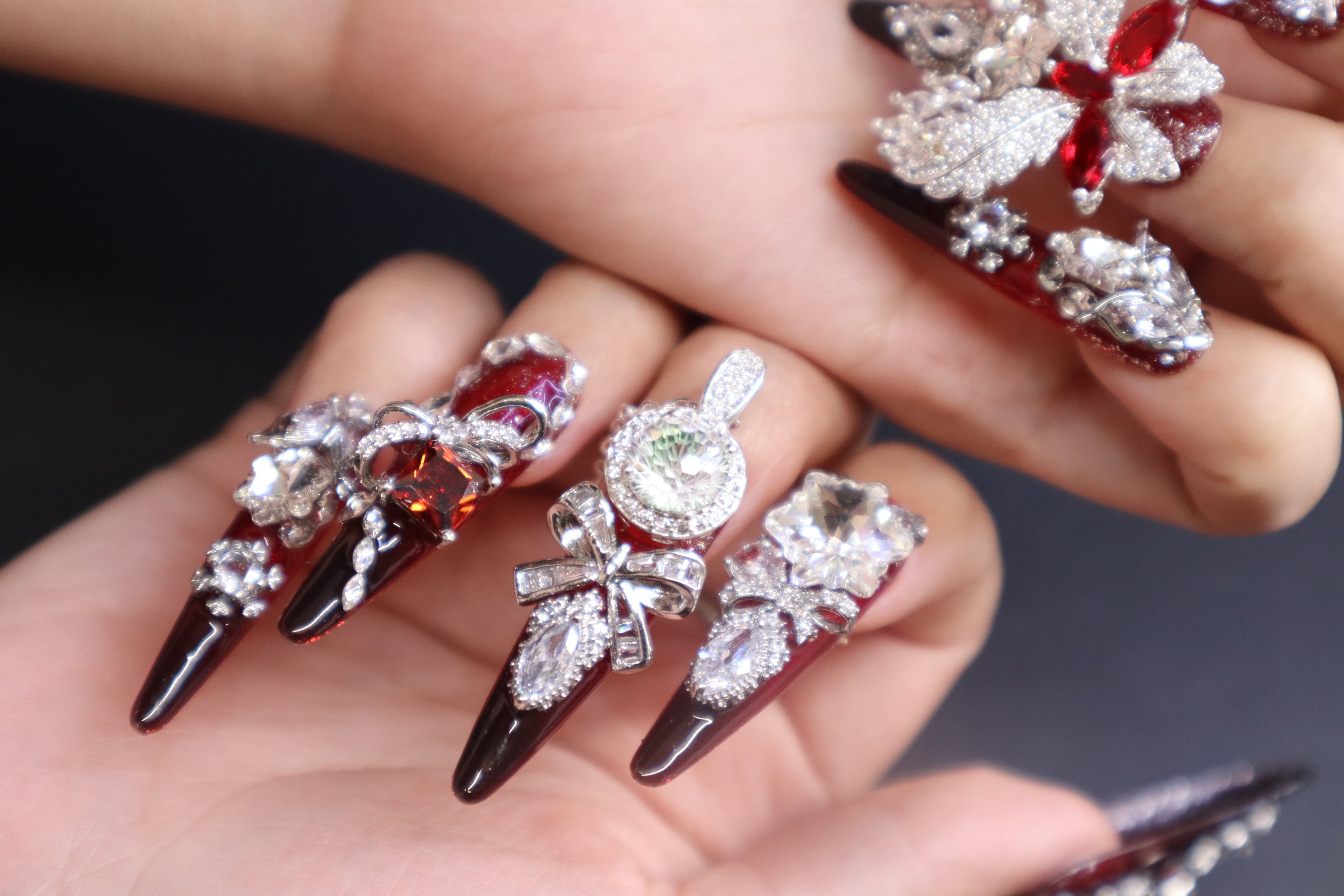 Luxury crystal press-on nails with blood-red gemstone, silver wing design, and disco crystal detail