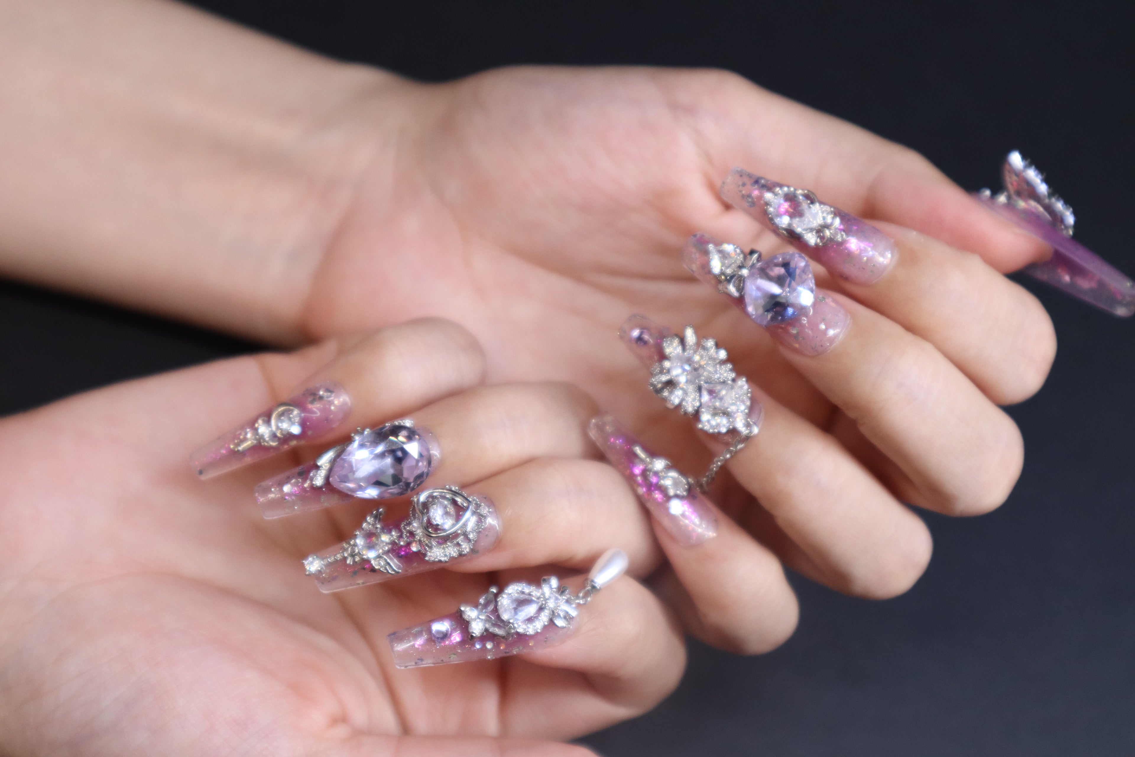 Lilac Heartbeat purple press-on nails with sheer glitter base, lilac blush gradient, butterfly crystal accents, and movable heart charm design.