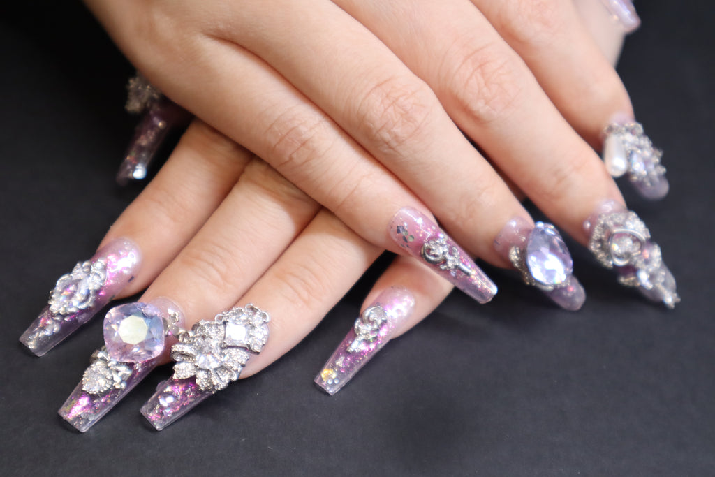 Lilac Heartbeat purple press-on nails with sheer glitter base, lilac blush gradient, butterfly crystal accents, and movable heart charm design.