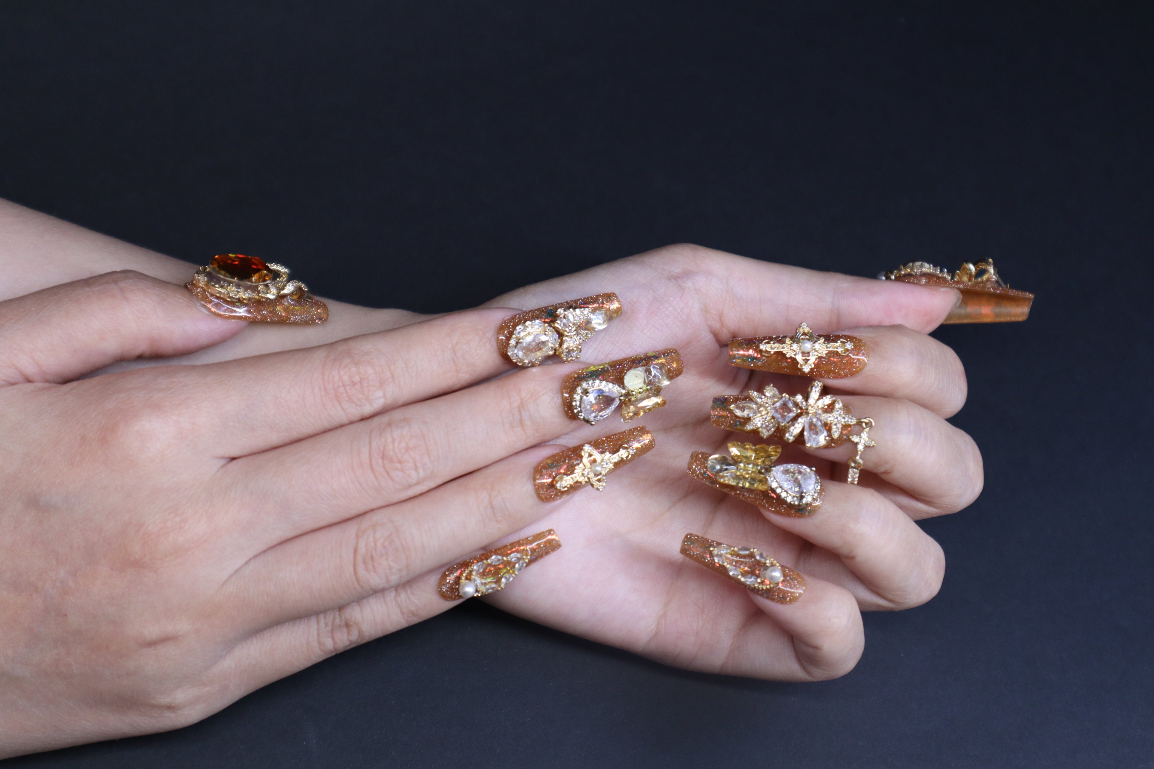 Golden Fortune press-on nails with amber brown tones, gold glitter, and crystal embellishments