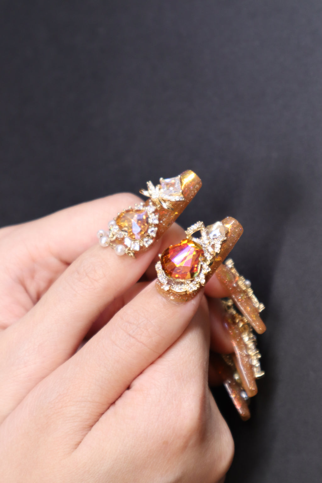 Golden Fortune press-on nails with amber brown tones, gold glitter, and crystal embellishments
