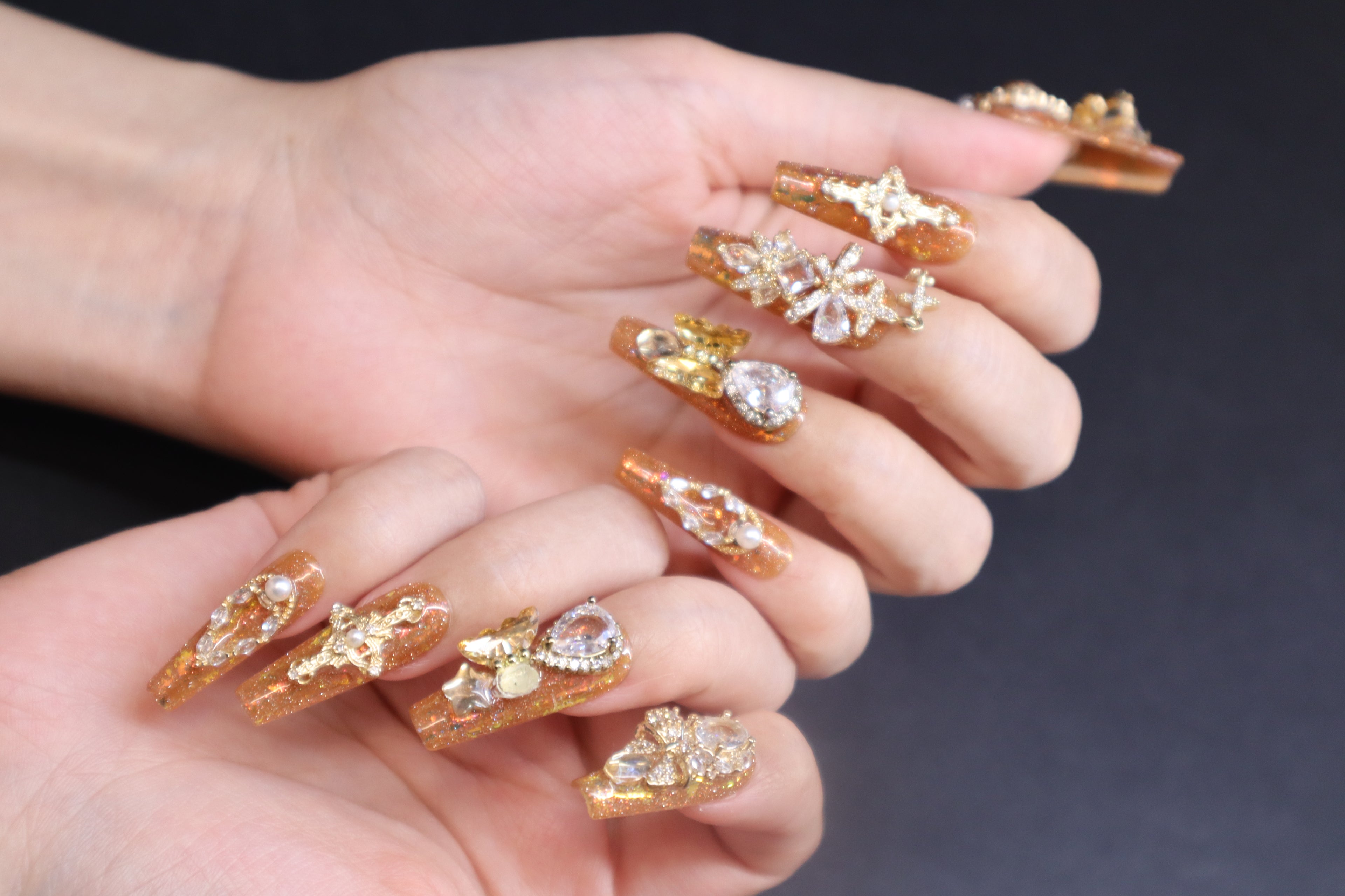 Golden Fortune press-on nails with amber brown tones, gold glitter, and crystal embellishments