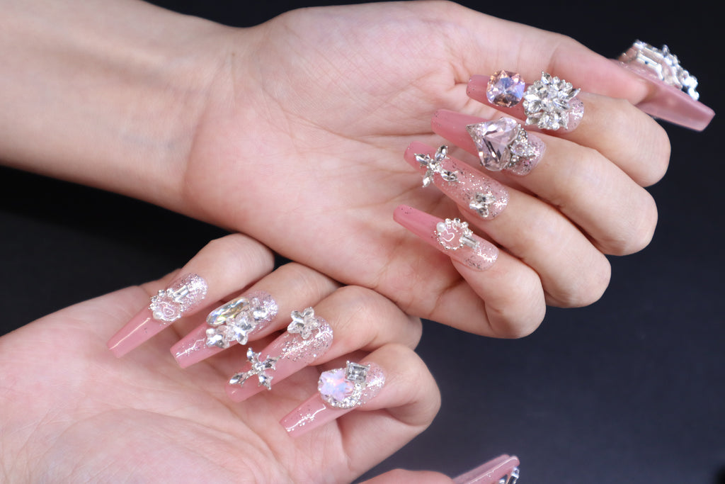Sweet pink crystal press-on nails with heart-shaped gem and soft feminine finish on hands