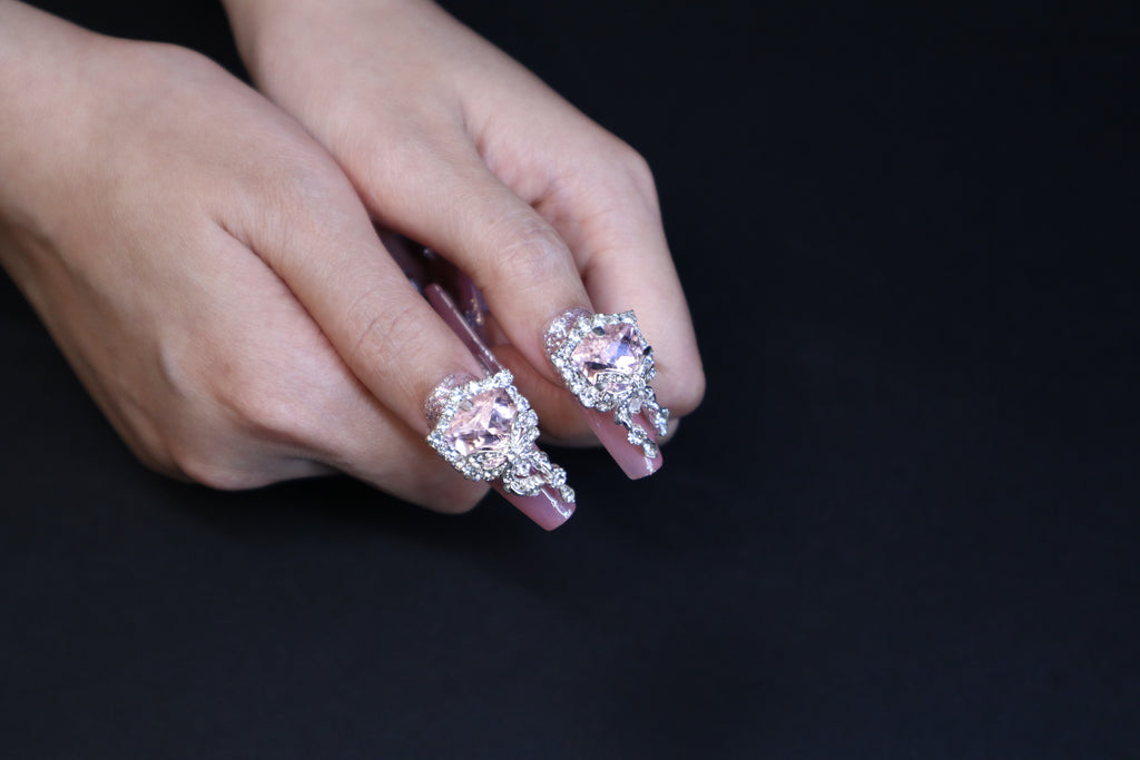 Girly pink press-on nails featuring cube-cut crystal and frosted star gems on hand