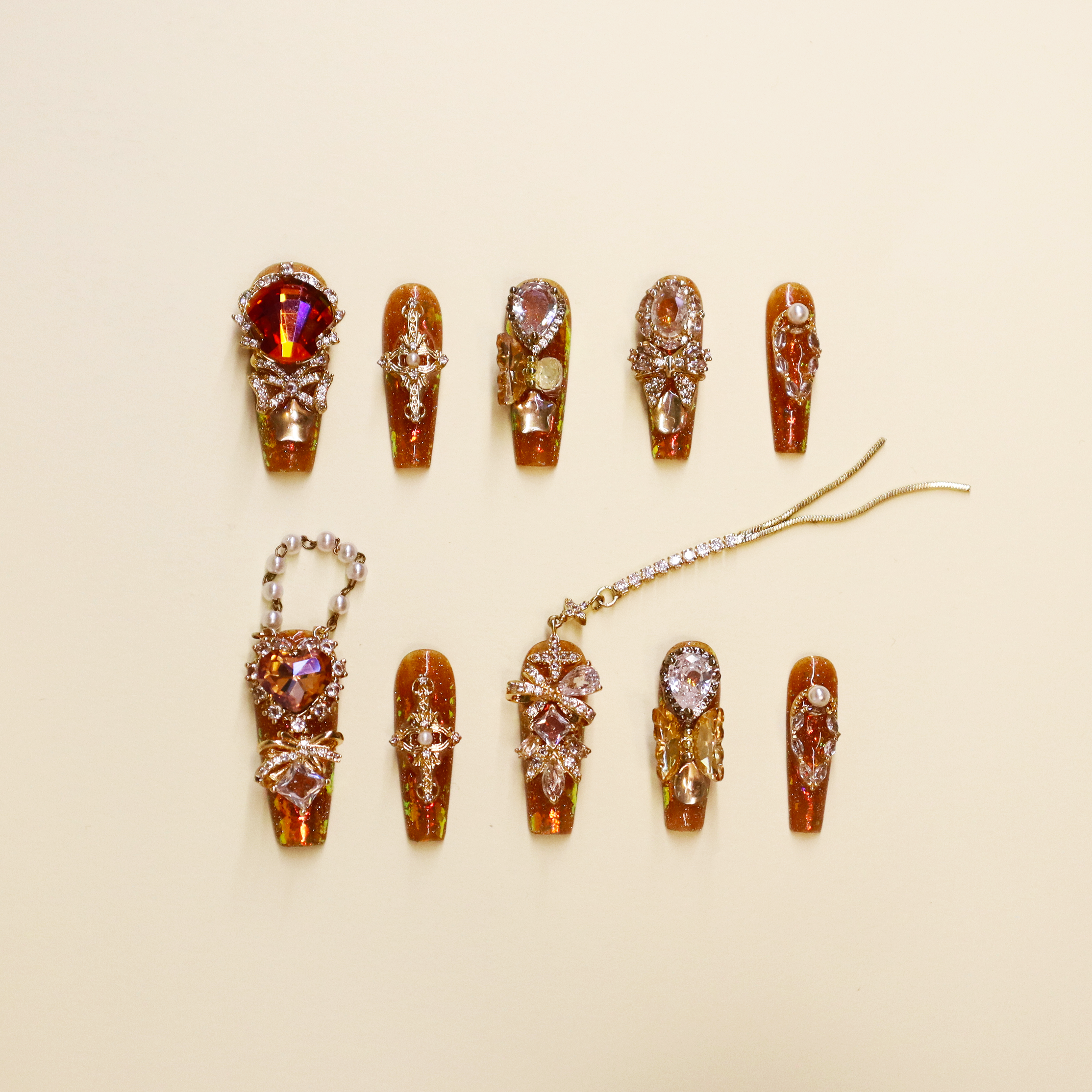 Golden Fortune press-on nails with amber brown tones, gold glitter, and crystal embellishments