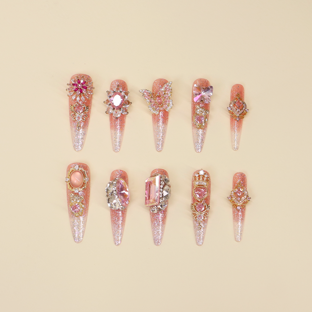 Luxury pink press on nails with rose gradient base, fine shimmer, heart and butterfly details, and pink crystal embellishments inspired by Les Petits Secrets